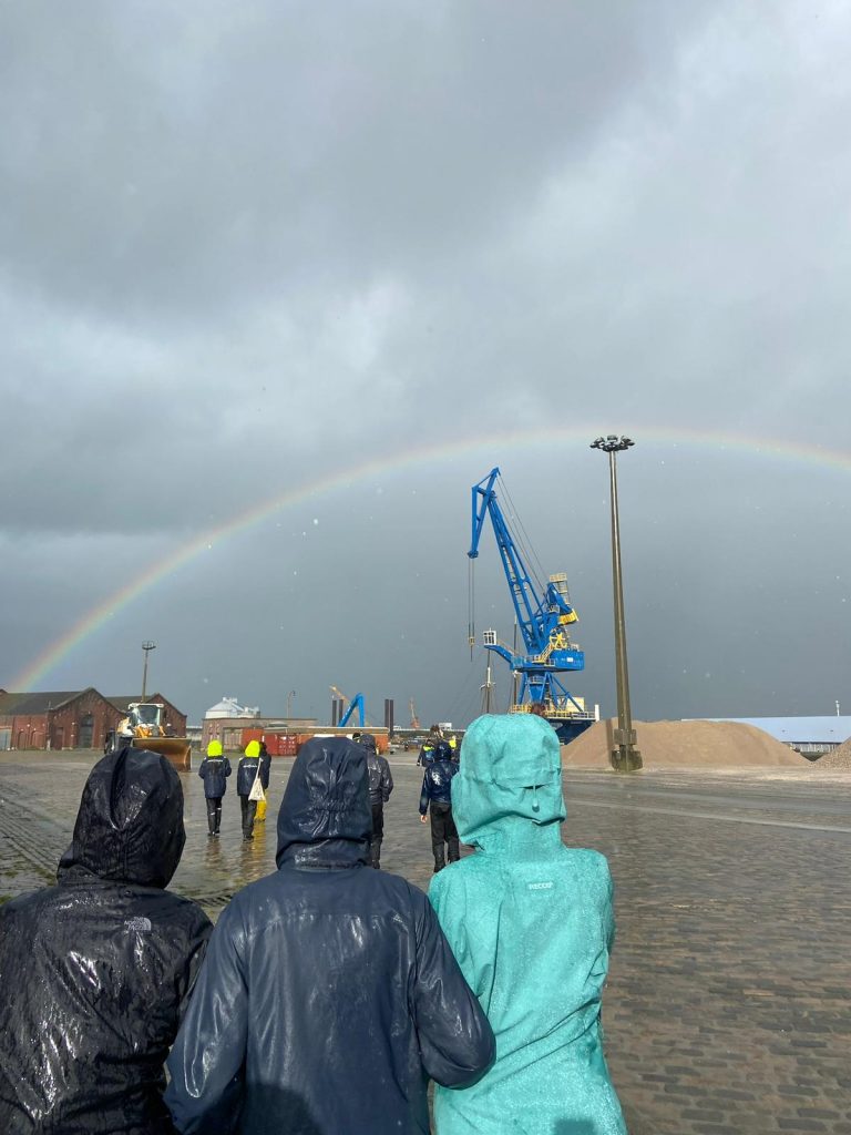 Schüler*innen laufen unter einem Regenbogen.