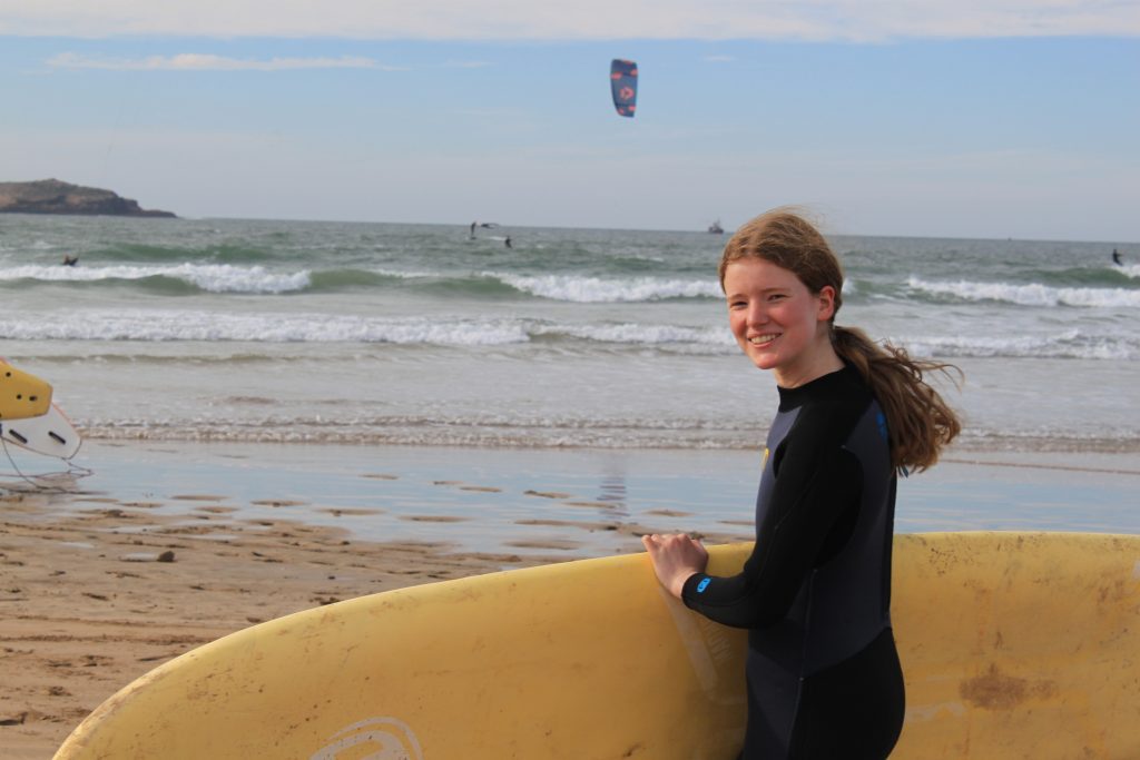 Schülerin trägt ihr Surfbrett ins Wasser