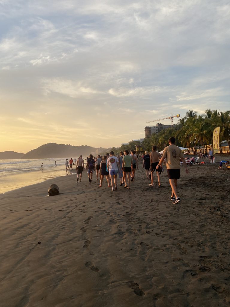 Schüler*innen laufen im Sonnenuntergang am Strand