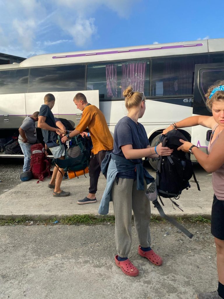 Schüler*innen packen ihr Gepäck in einen Bus.